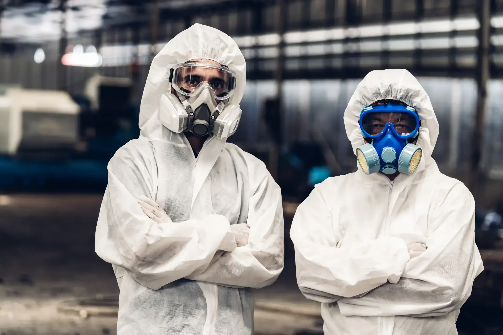 To personer i beskyttelsesdrag og masker står i industriel rengøring.